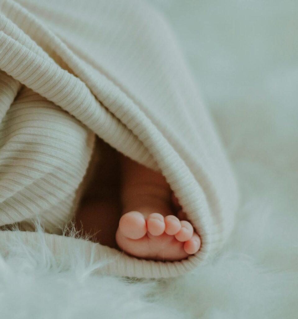 Adorable newborn baby foot wrapped in a soft, cozy blanket, capturing the essence of new life.